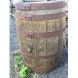 An oak whiskey barrel with staves bound by six riveted metal strap bands. (34.5in)