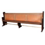 A rectangular mahogany pew, the panelled back with hymnbook shelf above a solid chamfered seat,