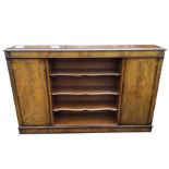 A mahogany cabinet with crossbanded moulded top above a central section of open adjustable scalloped