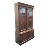 A mahogany gun cupboard with moulded cornice above astragal glazed doors framed by ribbed pilasters,