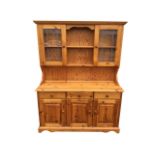 A pine kitchen dresser, the back with moulded cornice above open shelves flanked by leaded glass