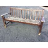 A rectangular hardwood garden bench with slatted back and seat, having shaped platform arms raised