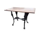 A rectangular oak table on cast iron base, the legs cast with masks on paw feet, joined by twin