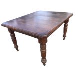 An extending Victorian oak dining table with spare leaf, the canted moulded top supported on