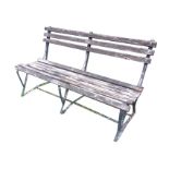 A wrought iron garden bench with shaped wood slatted back & seat, raised on triangular frame