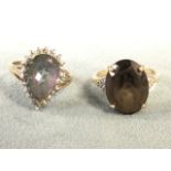 A 9ct gold ring claw set with oval smokey quartz stone in raised cage above triangular panels of