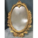 A heavy Victorian oval bronze mirror in ribbed and moulded ribbon bound frame surmounted by a ribbon