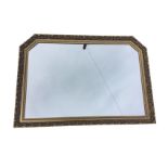 A gilt framed rectangular overmantel style mirror with canted top corners, the frame with foliate