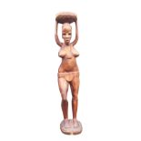 A carved African figural stand formed from a solid trunk, with tribal girl holding vessel on her