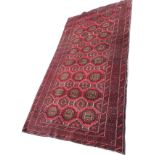 A Belouchi rug woven with grid of octagonal medallions on red ground with hooked rims, the frieze of