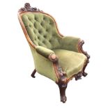 A Victorian mahogany button upholstered armchair with carved crest above an arched moulded back, the