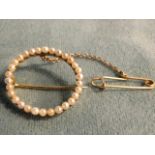 An antique circular pearl brooch with thirty pearls set into gold ring, with hinged pin to verso -