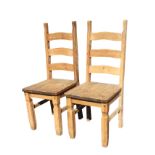 A pair of pine ladderback chairs with long plank seats on square shaped column legs joined by