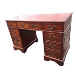 A reproduction mahogany kneehole desk with gilt tooled leather skivers to rectangular moulded top,