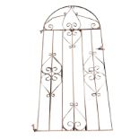 An arched wrought iron garden gate, the vertical tubular spindles with scrolled decoration. (35in