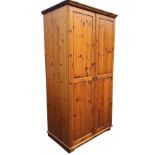 A reproduction Victorian style pine wardrobe with moulded cornice above a pair of fielded panelled