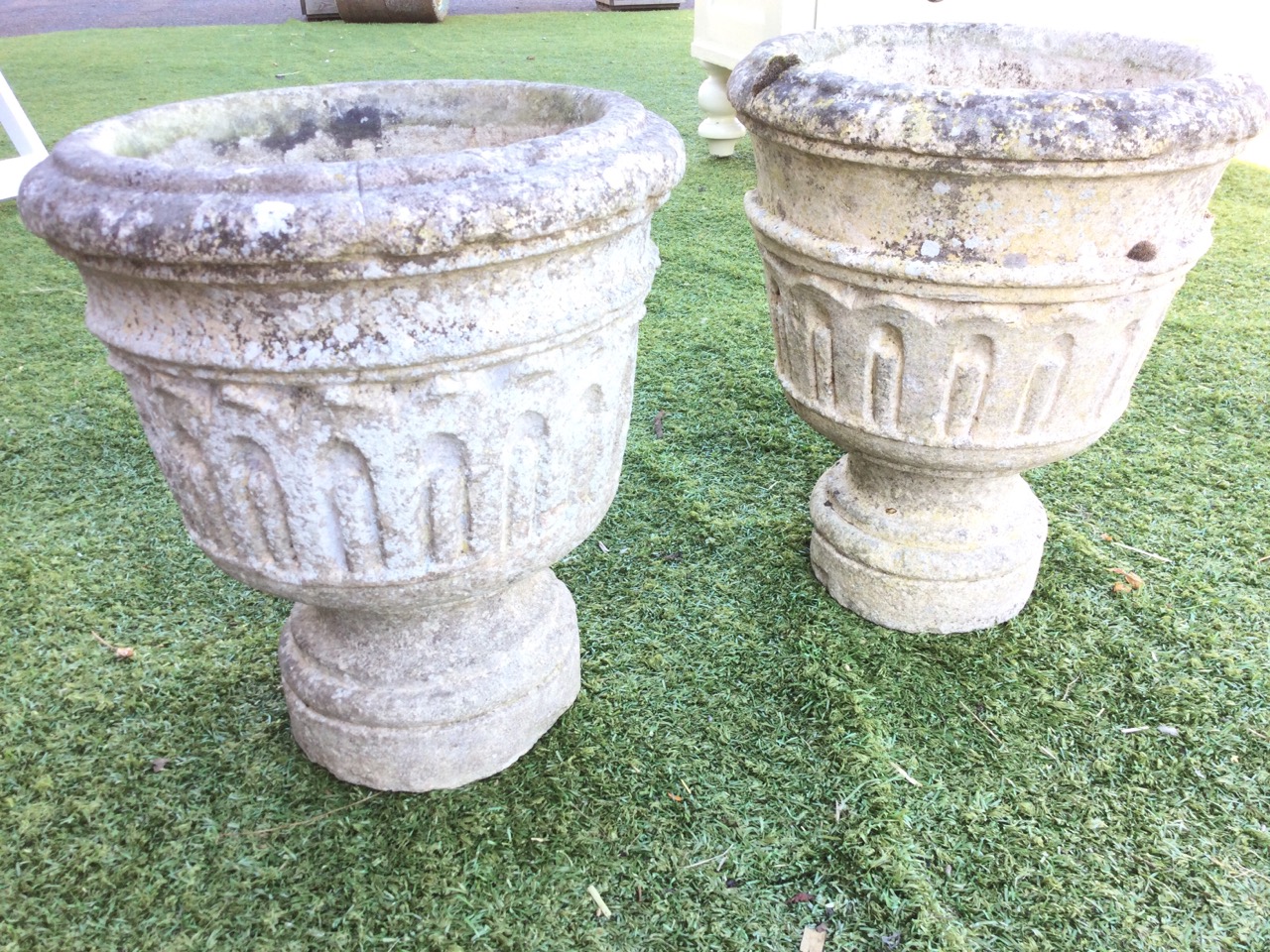 A pair of composition stone urns with moulded rims above tapering fluted bucket shaped pots, - Image 3 of 3