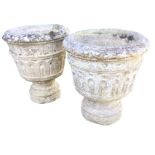 A pair of composition stone urns with moulded rims above tapering fluted bucket shaped pots,