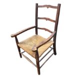 A country ladderback armchair with shaped rails and platform arms above a rush seat, raised on