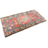 An antique Turkish rug woven with madder field of scrolled foliage centered by circular