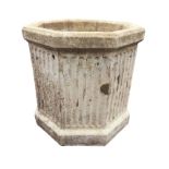 A large hexagonal composition stone well-head style garden urn with chamfered rim and fluted body