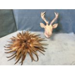 A stylised moulded stags head with wood grain type finish; and a circular pheasant feather