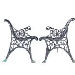 A pair of cast iron bench ends with scrolled backs and arms supported on pierced lionhead