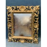 An Italian carved and burnished giltwood mirror, the rectangular plate in lozenge moulded frame