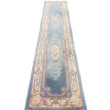 A Chinese thick pile wool runner woven with two scrolled floral medallions on pale blue ground,