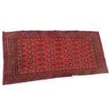 A small Turkish rug woven with field of stepped lozenge medallions on madder ground, framed by