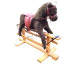 An English made Pegasus rocking horse with leather bridle and upholstered body, raised on pine stand