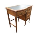 An oak desk with leatherette writing surface to moulded top, having bowfronted frieze drawer flanked
