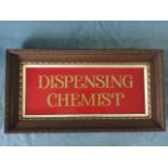 An oak framed glass advertising sign, Dispensing Chemist, in gilt on red ground with silvered