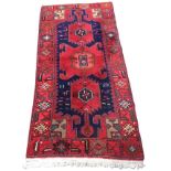 A contemporary rectangular Turkish rug woven with three linked red floral medallions on blue