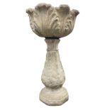 A composition stone garden urn on stand, the circular leaf moulded bowl supported on a fluted