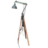 An old brass anglepoise style floodlight on tripod stand, with bowl shaped shade on sprung arms