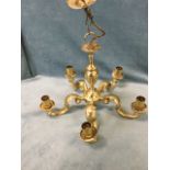 A heavy brass light fitting with column hung from ring by chain beneath circular ribbed ceiling