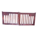 A pair of stained driveway gates with slatted panels in deep frames, with original galvanised