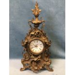 A gilded French style mantleclock with scrolled leaf cast case surmounted by a floral urn finial,