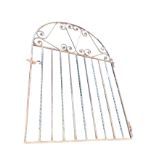 A wide arched wrought iron garden gate with scroll decorated panel above alternating square and