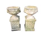 A pair of composition stone urns on stands, the circular bowls cast with floral fruit swags above