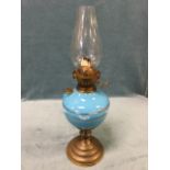 A C20th oil lamp with circular moulded base supporting a ceramic blue glazed reservoir, having