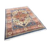 A Herat style Belgian made wool rug woven with floral orange star medallion on fawn ground with blue