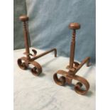 A pair of antique wrought iron fire dogs with bun-shaped finials to square columns having sliding