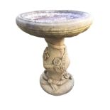 A composition stone garden birdbath with circular ribbed bowl on baluster shaped column embossed