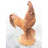 A cast iron cockerel, the bird modelled perched on foliage above circular moulded plinth. (17.5in)