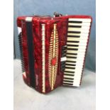 A cased Baile Parisienne accordion, with three octave keyboard and red marbleised body, mounted with