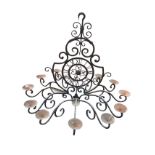 A large wrought iron candlelight with scrolled panel framing a clockface with roman chapters,