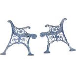 A pair of scroll cast iron bench ends, the arms supported on pierced flowerhead roundels, raised