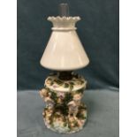 An European porcelain oil lamp, heavily encrusted with flowers, the reservoir in bowl supported by